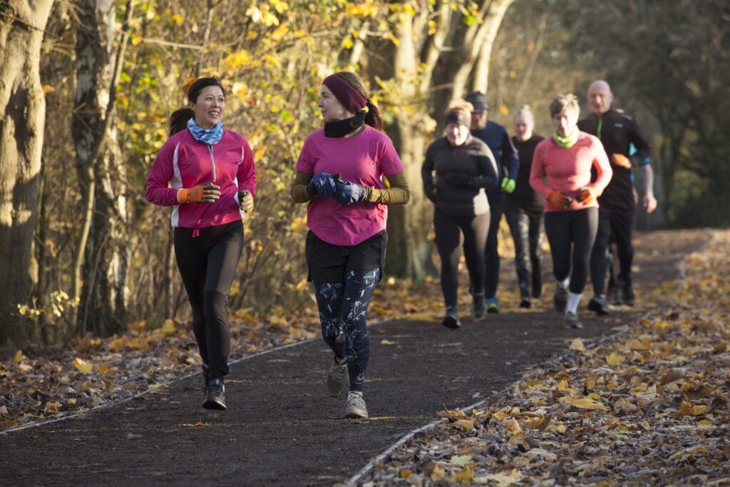 group of adults jogging together on a leaf strewn 2025 04 05 05 59 29 utc